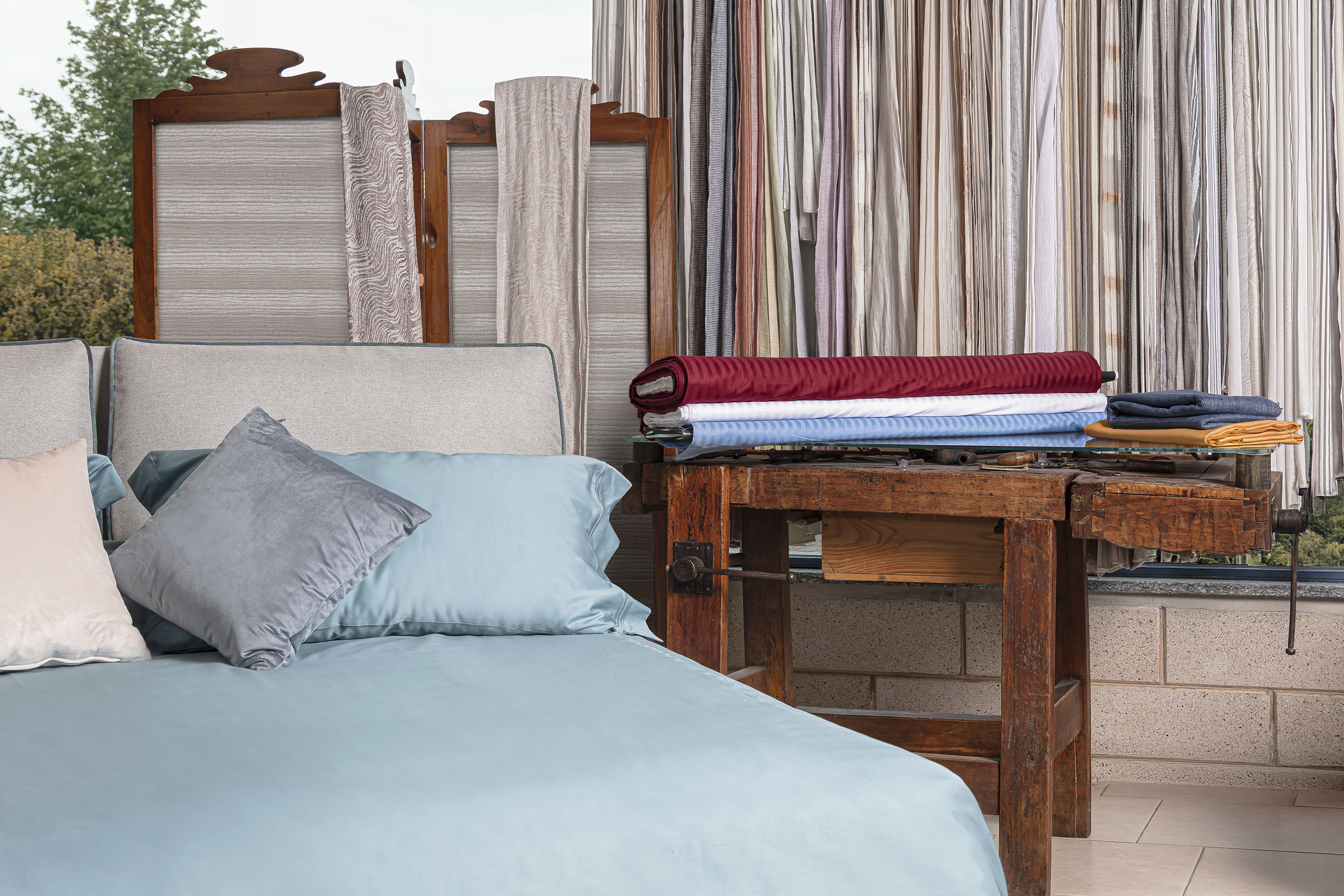 Letto con materasso rifinito e tessuti per tende su banco da lavoro.